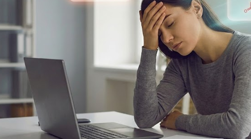 Exhausted person at a desk with digital overlays of low ATP energy and vitamin deficiencies.
