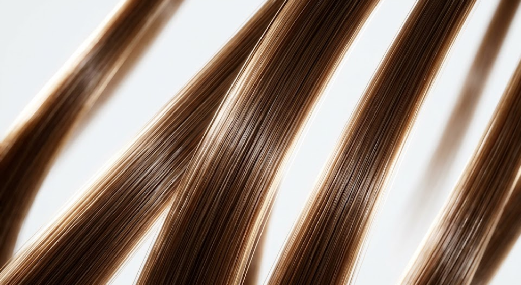 Extreme macro photography of multiple thick, strong, and highly glossy human hair strands.