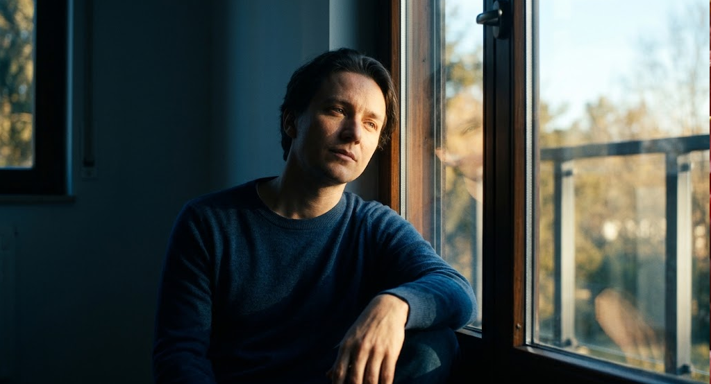 Person sitting by a window showing the stark contrast between Vitamin D deficiency fatigue and mental clarity.